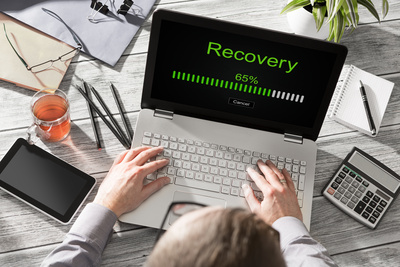 image of a person sat with a laptop on their lap with disaster recovery written on the laptop screen